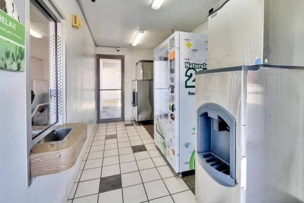 A hallway with a tiled floor, a sink, and a refrigerator.