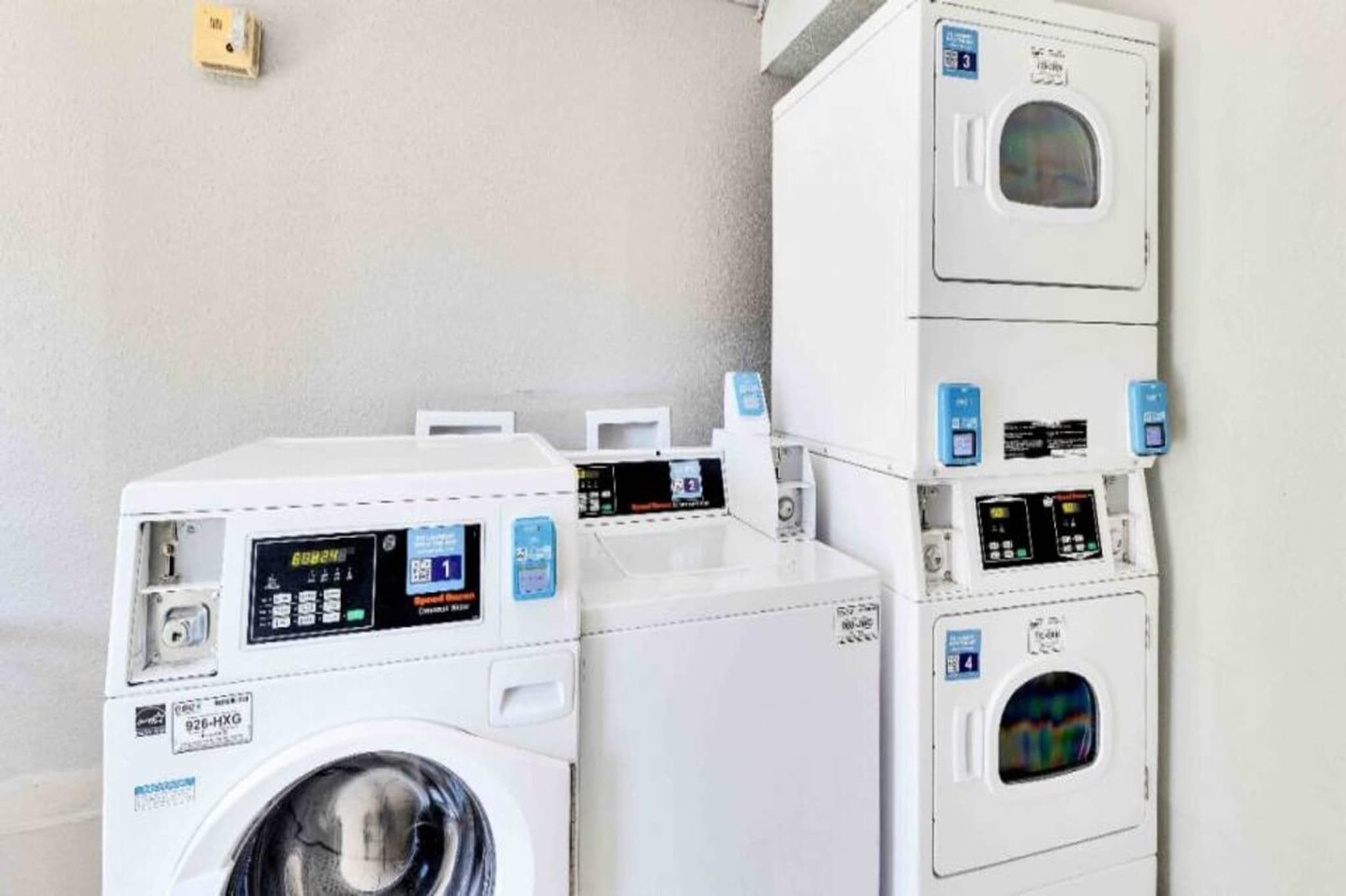 A laundry facility with multiple washing machines and dryers, including digital displays and control panels.