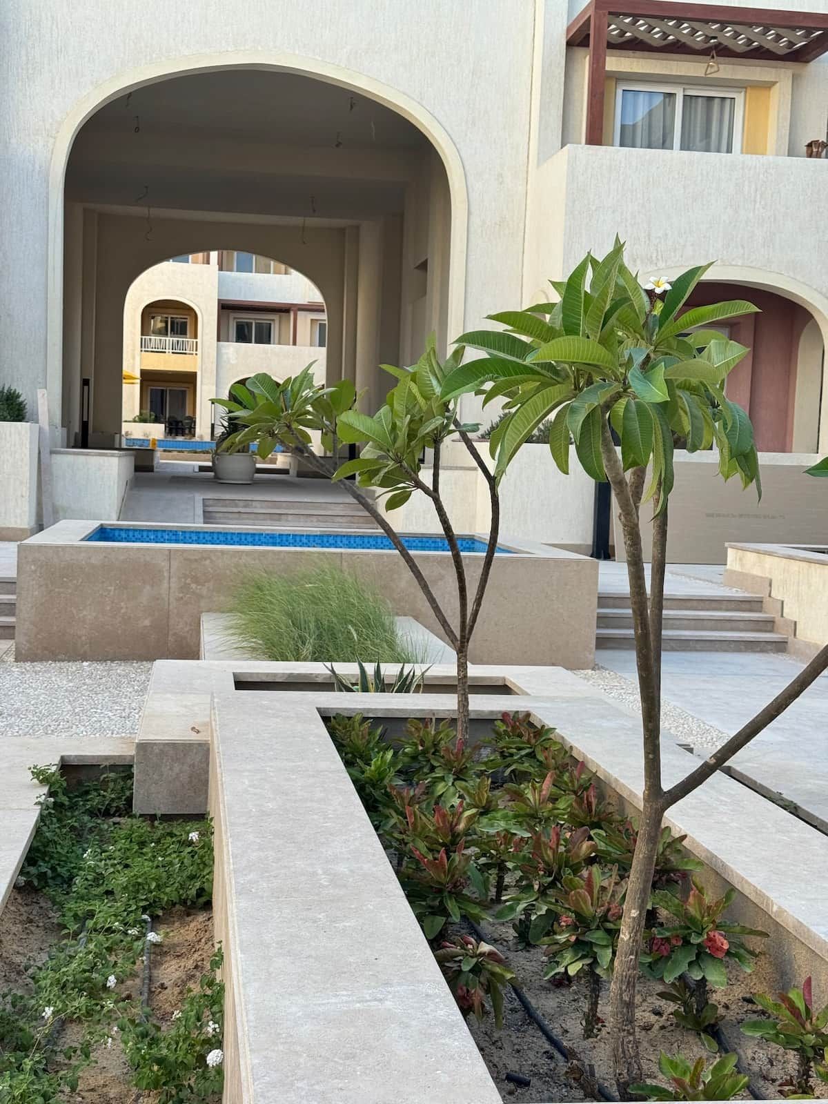 Un bâtiment moderne doté d’une piscine, d’un espace extérieur aménagé pour se détendre et d’un jardin paysager.