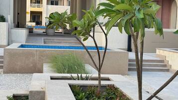 Ein modernes Gebäude mit Pool, Außenbereich zum Sitzen und einem angelegten Garten.