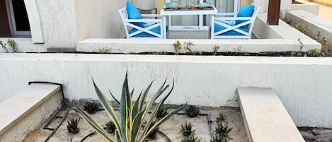 Un espace extérieur aménagé avec une table et des chaises, une pergola et un jardin planté.