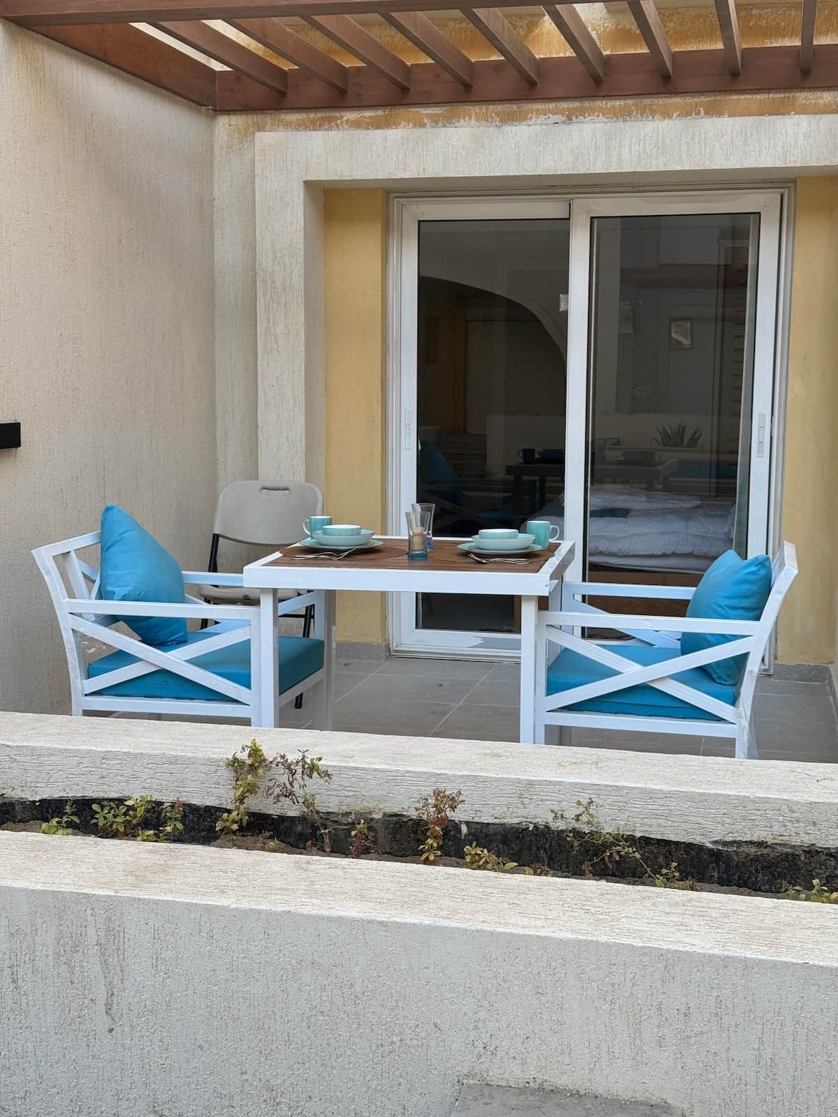 A patio area with a table and two chairs, a sliding glass door, and a view of the interior.