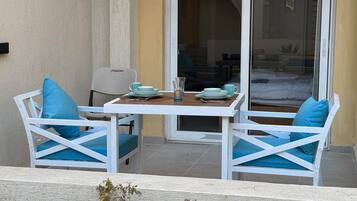 A patio area with a table and two chairs, a sliding glass door, and a view of the interior.