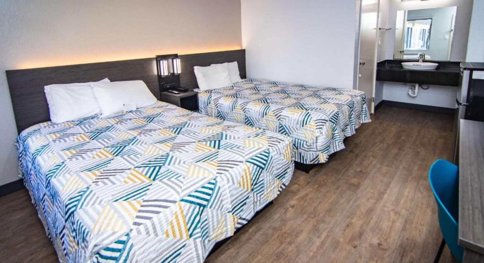 Une chambre d’hôtel avec deux lits, un bureau et une salle de bain.