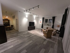 Ein Wohnzimmer mit Fernseher, einer Couch und einem Essbereich mit Tisch und Stühlen.