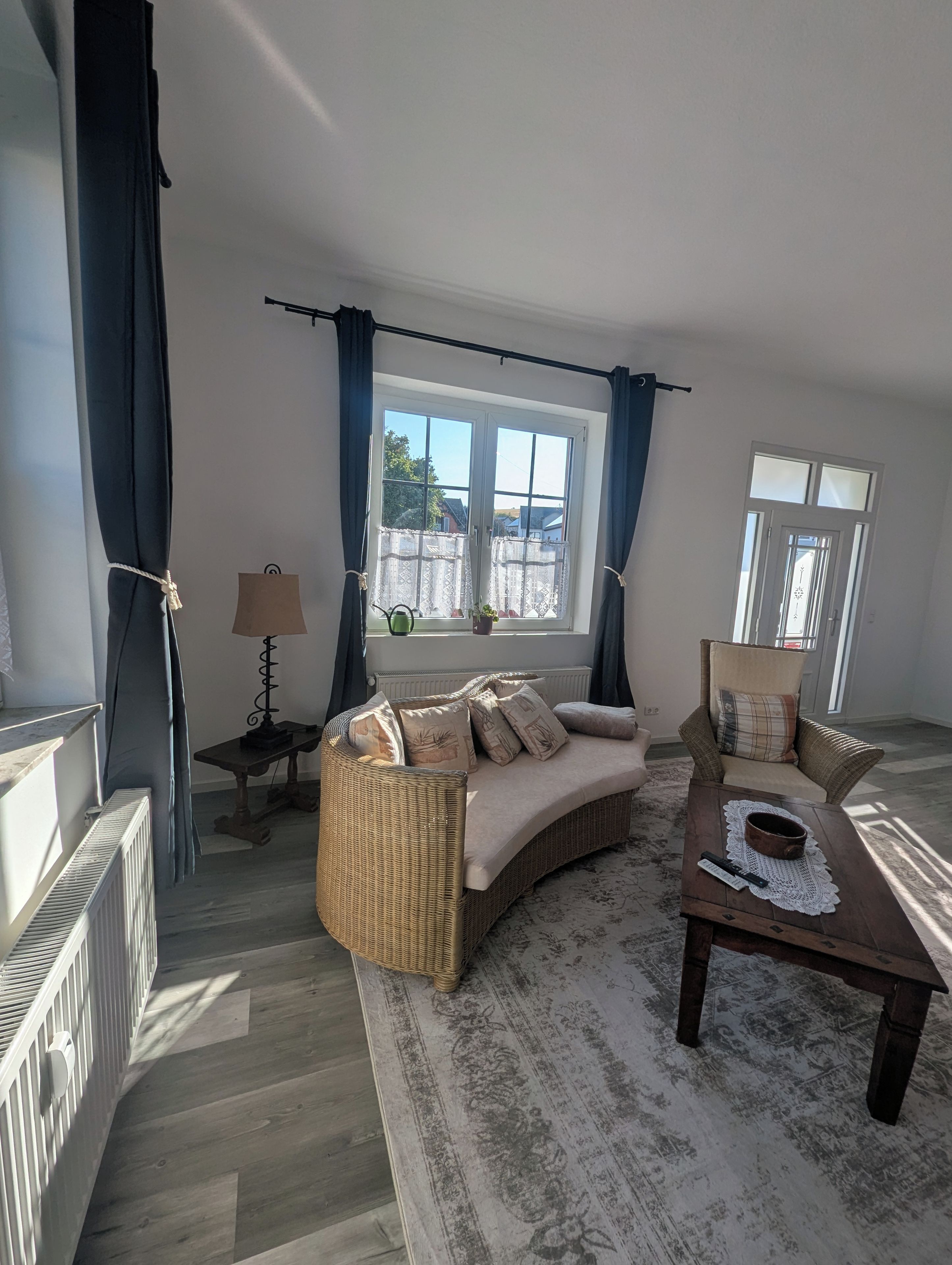 A furnished living room with a sofa, armchairs, a coffee table, and a window with curtains.