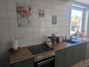 Eine Küche mit Holzarbeitsplatte, integriertem Backofen und einem Fenster mit Blick nach draußen.