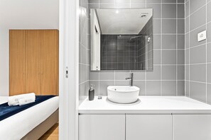 A modern bathroom with a white sink, a mirror, and a shower. - Guestready - Poetikblue Residences (Porto)
