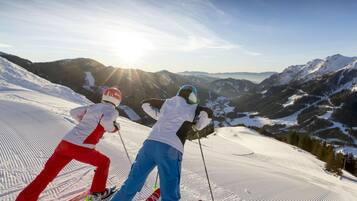 Two skiers on a snowy slope with a mountain view in the background.