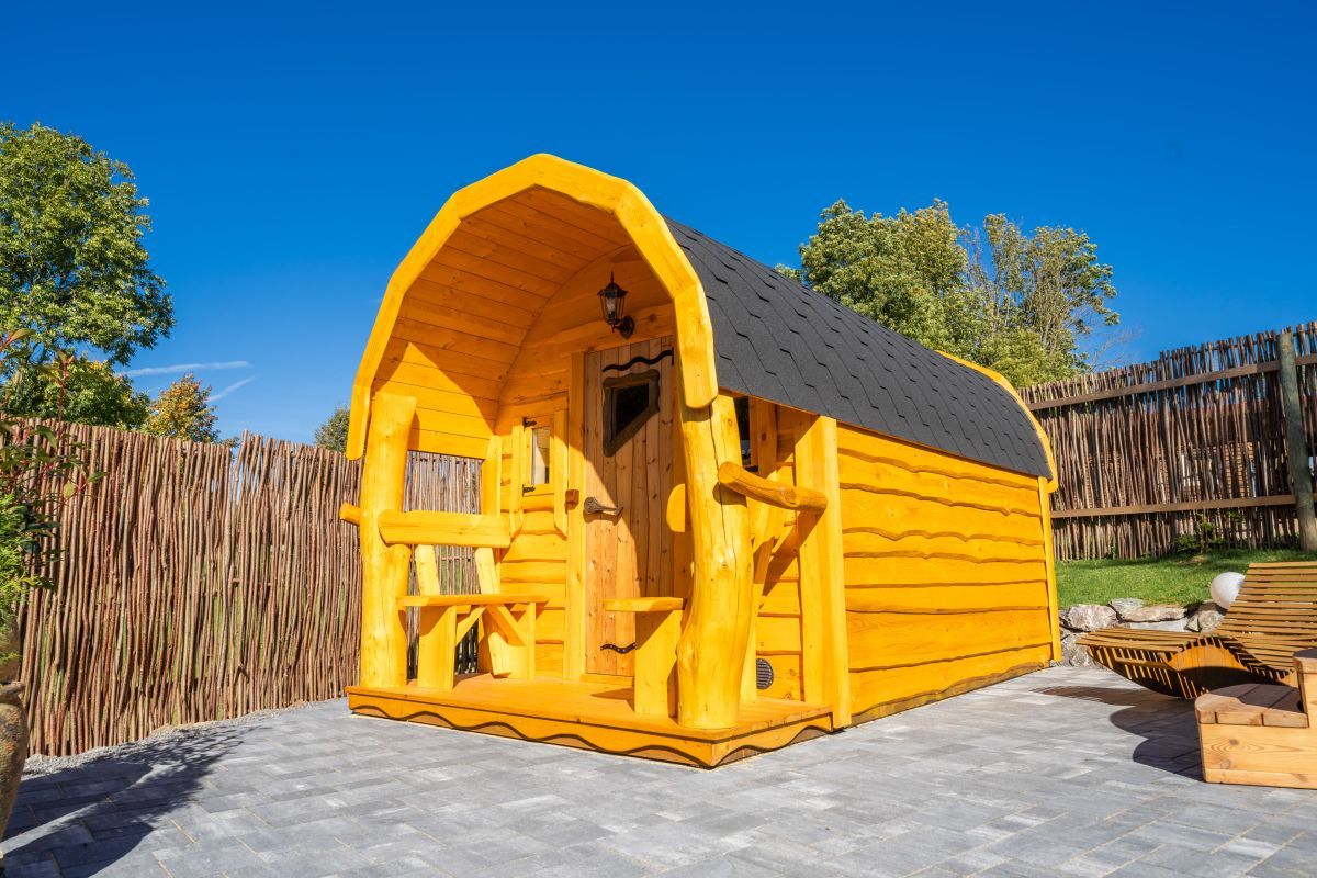 Eine Holzhütte mit geneigtem Dach, einer Tür und einem Fenster.