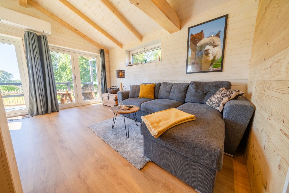 A cozy living room with a grey sofa, a small round table, and a framed picture on the wall.