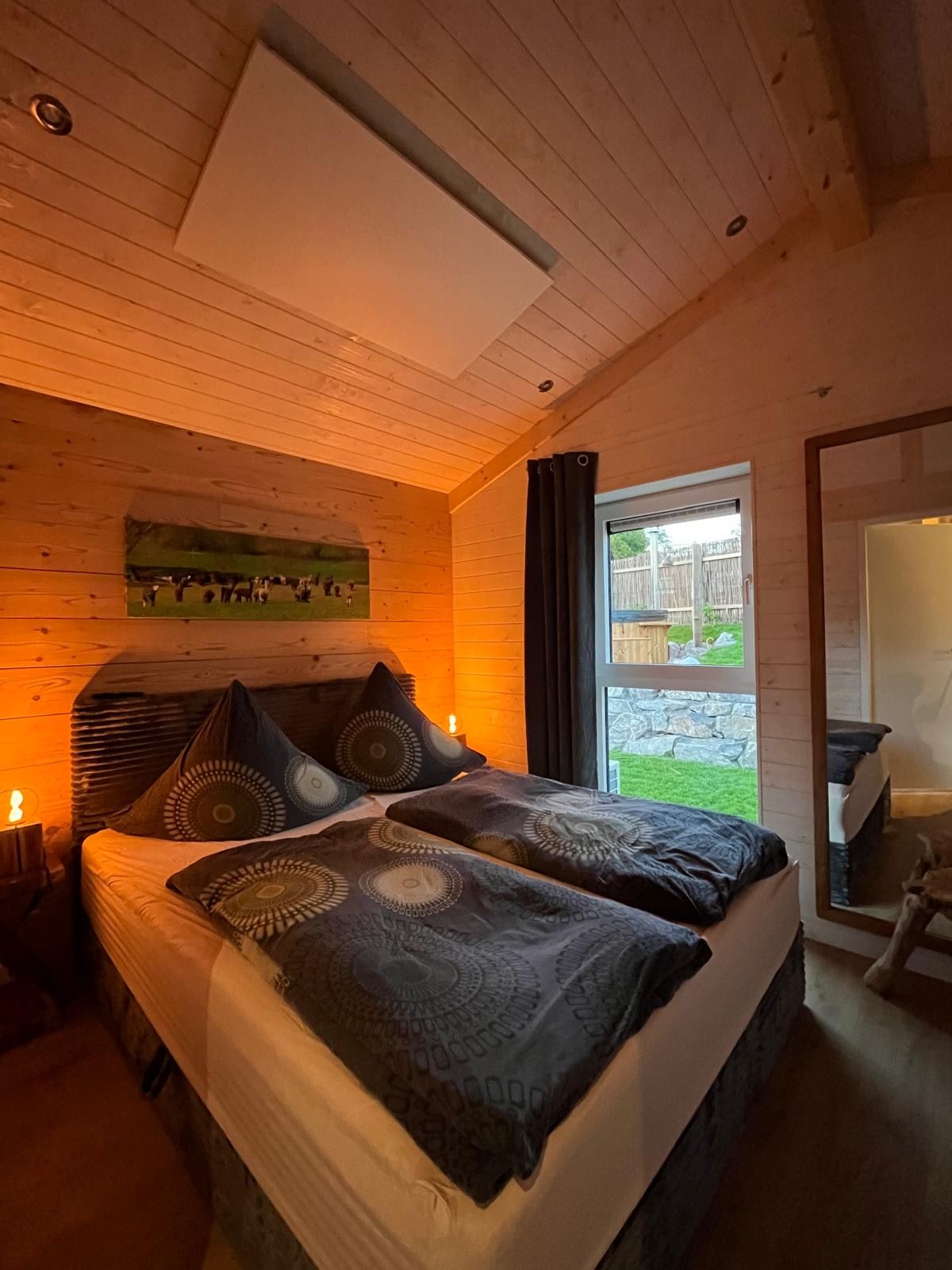 Een slaapkamer met een bed, kussens, een nachtkastje en een raam.