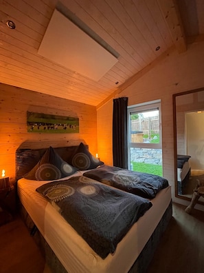 A bedroom with a bed, pillows, a nightstand, and a window.