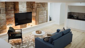 A modern living room with a stone fireplace, a flat-screen TV, a sofa, and a coffee table. - Joivy Vaults  (Edinburgh)