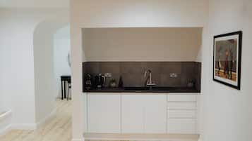 A compact kitchen with a built-in sink, a coffee maker, and a small table.