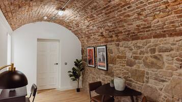 A room with a stone wall, a white door, a table with chairs, and a potted plant.