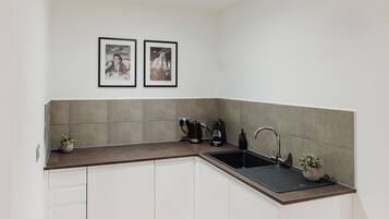A kitchen with a sink, a coffee maker, and two framed pictures on the wall.