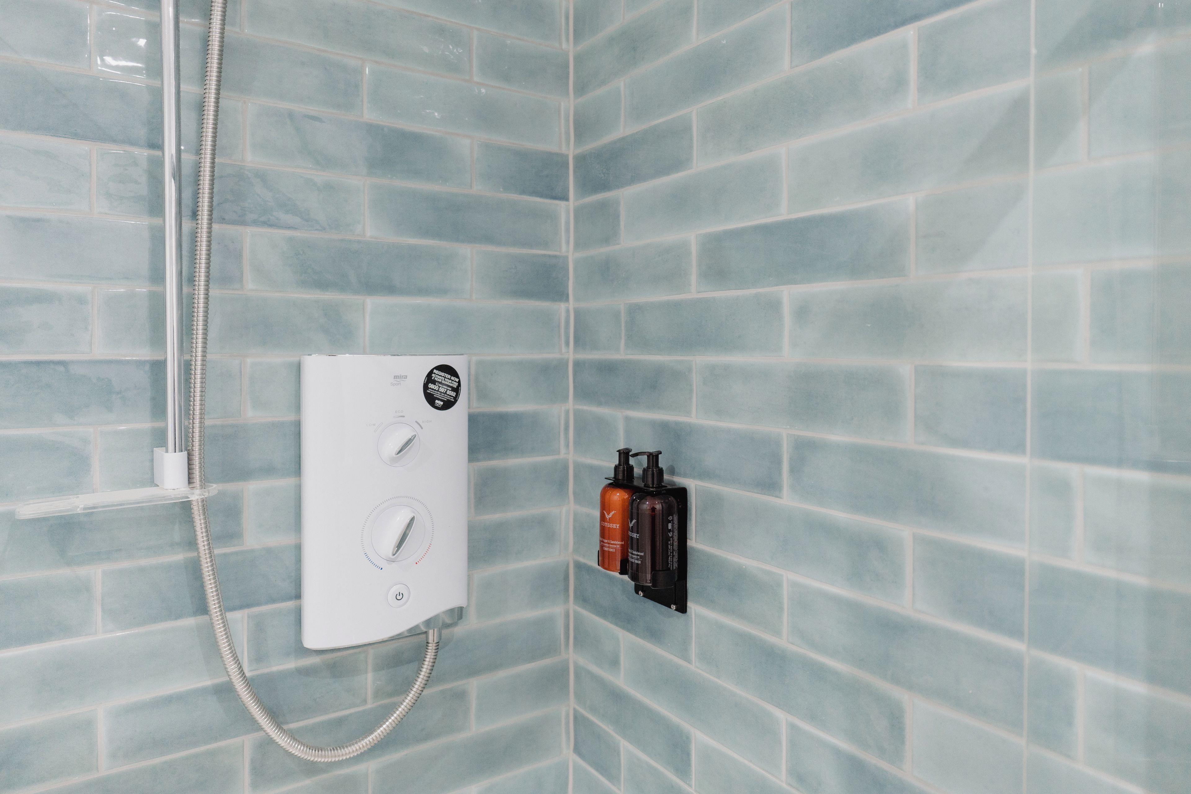 A shower area with a control panel and two bottles of toiletries.