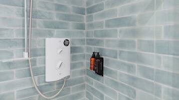 A shower area with a control panel and two bottles of toiletries.