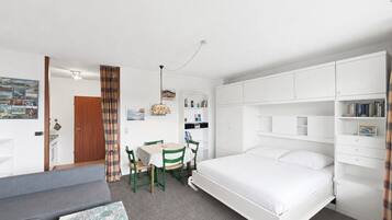 A room with a bed, a desk, a chair, and a sofa.