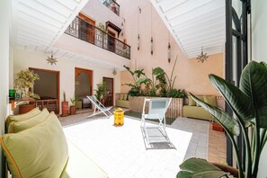 A spacious indoor area with a high ceiling, a pool, and multiple seating areas with chairs and a sofa. - Riad Le Bertal - Private Beldi Chic Riad with Pool & Sunset Rooftop in Medina (Marrakech)