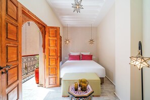 A hotel room with a bed, a nightstand, a star-shaped hanging light, and a wooden door. - Riad Le Bertal - Private Beldi Chic Riad with Pool & Sunset Rooftop in Medina (Marrakech)