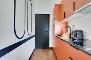 Une cuisine moderne équipée d’une machine à café, d’un panier de fruits et d’une bouteille de jus d’orange.