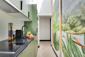 A modern kitchen with a built-in stove, a coffee machine, and a fruit basket on the counter. - One-Bedroom Superior Apartment (Paris)