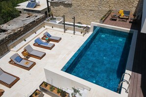 Una piscina en la azotea con sillones de descanso y vistas a la playa.