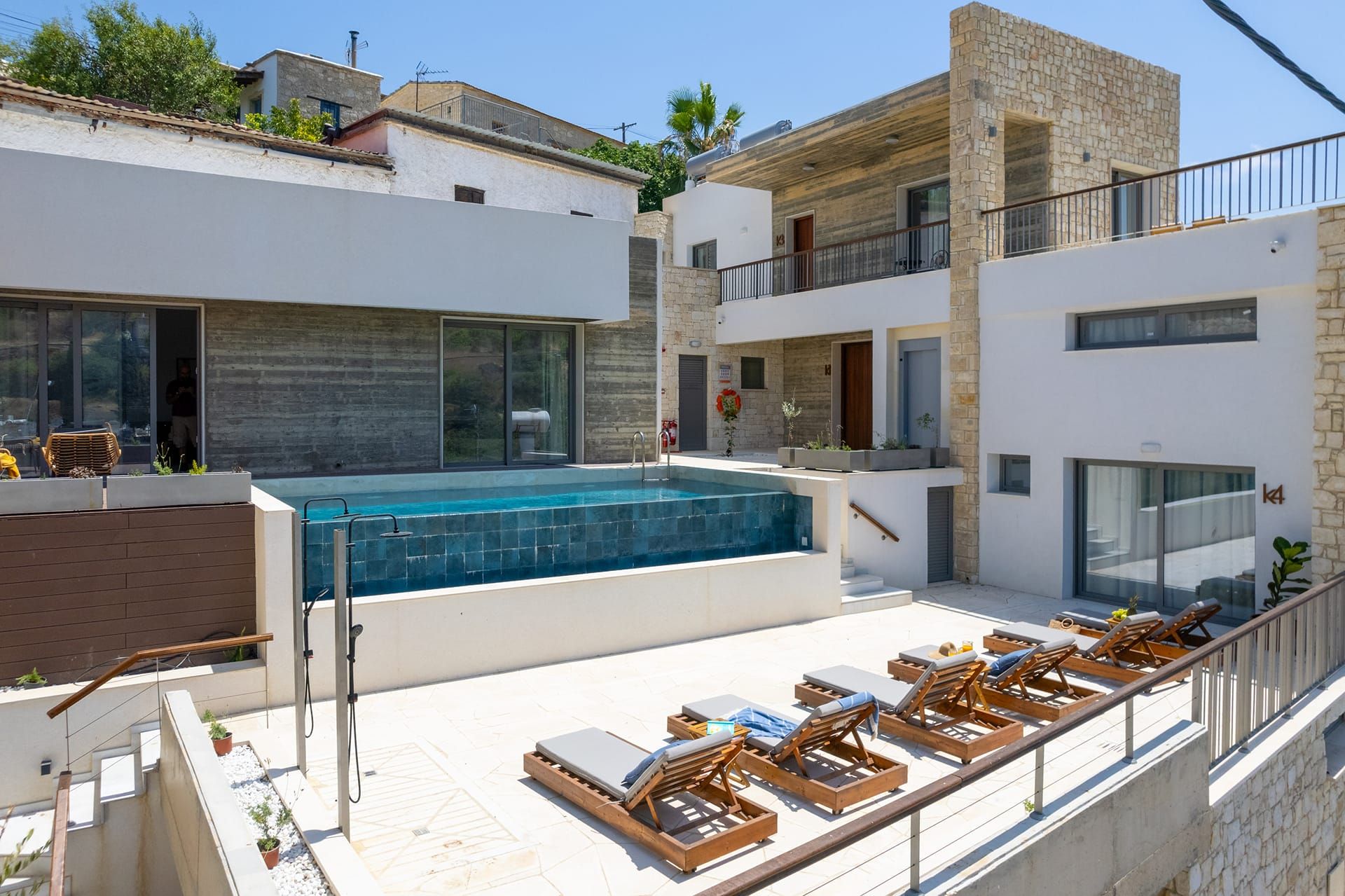 Zona de piscina exterior moderna con sillones de descanso y agua cristalina.