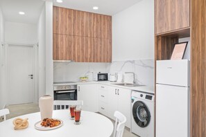 Ett modernt kök med träskåp, en mikrovågsugn, en kaffebryggare, en brödrost, en diskho och en tvättmaskin.