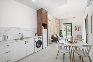 Eine moderne Küche mit integriertem Waschmaschine, einem Essbereich mit weißem Tisch und Stühlen sowie einer Steinwand.