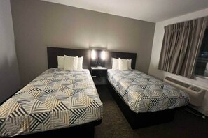 A hotel room with two beds, each with patterned bedding, a bedside table with a lamp, and a window with curtains. - Clean 2-Bed Room|Free Wifi&Parking (Junction)