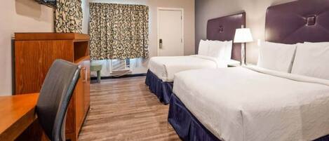 A hotel room with two beds, a desk, a chair, a TV, and a patterned curtain.
