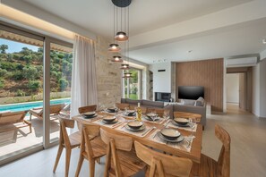 Un espace repas moderne avec vue sur la piscine, un téléviseur à écran plat et un mur en pierre.