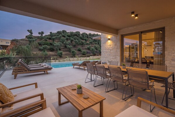 Eine Außenpatio mit Pool, Liegestühlen und einem Essbereich mit Stühlen und Tisch.
