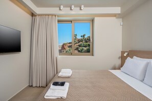 Ein Hotelzimmer mit Bett, Fernseher, Fenster und Blick auf eine Wüstenlandschaft, sowie einem Vorhang.