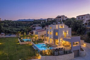 A modern villa with a swimming pool, outdoor seating, and a view of the surrounding landscape. - Villa Agapi is the largest residence of the La Divina Luxury Villas collection (Chania)