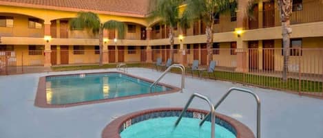 A hotel with a swimming pool, multiple balconies, and palm trees.