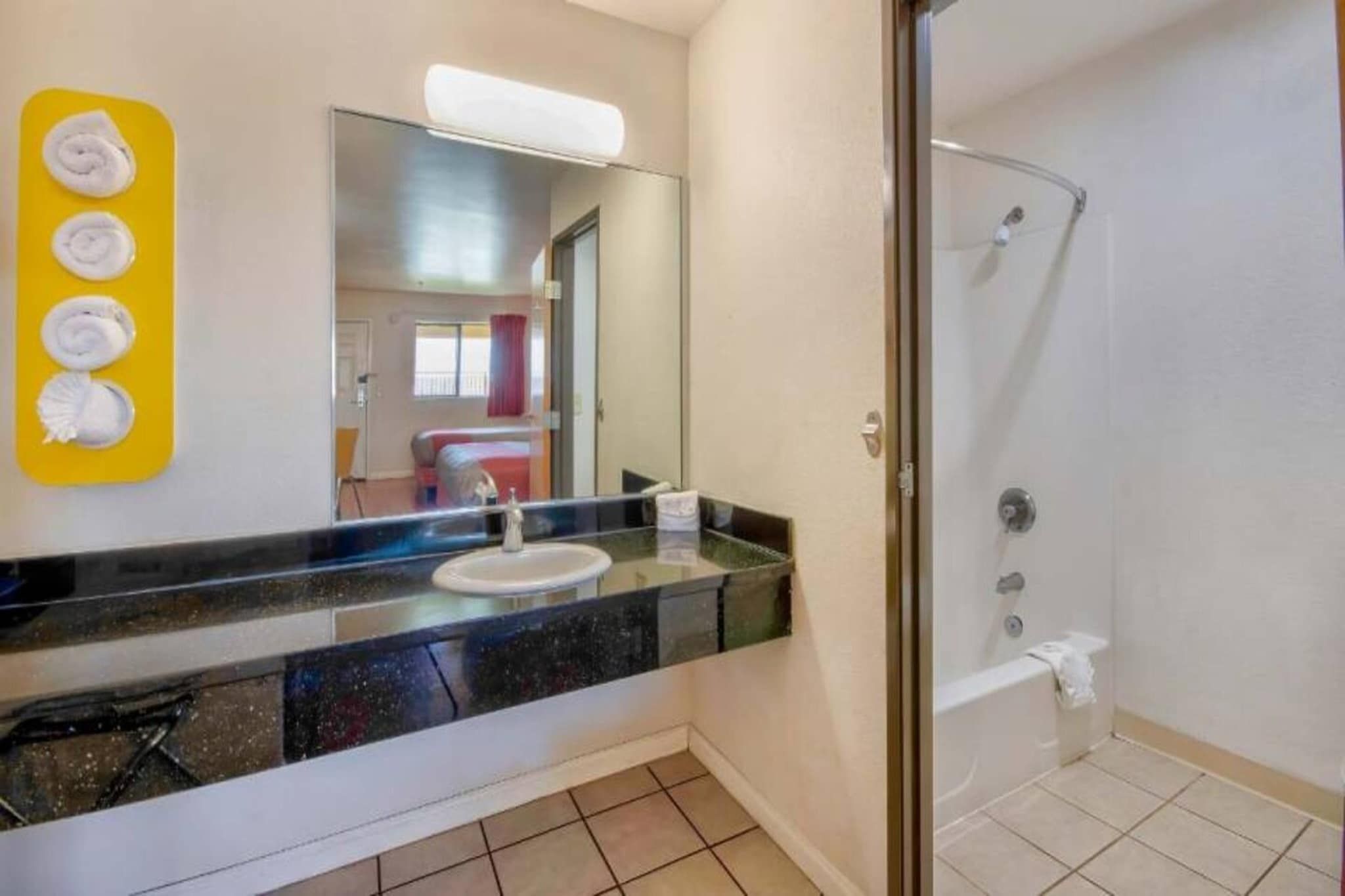A bathroom with a sink, mirror, and shower.