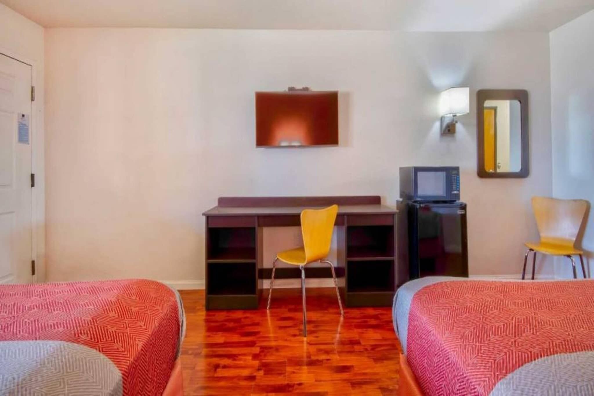 Une chambre d’hôtel avec deux lits, un bureau avec une chaise, une télévision et un réfrigérateur.
