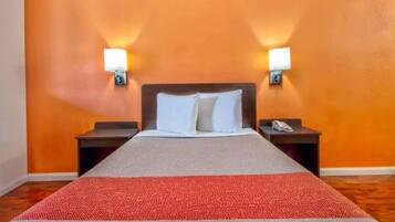 A hotel room with a bed, two bedside tables, and wall-mounted lamps.