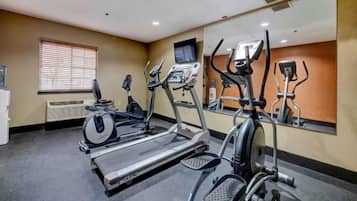 A gym with treadmills, elliptical machines, and a mirrored wall.