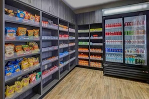 A snack and beverage section with shelves stocked with chips, cookies, and a refrigerated display with sodas and water. - 2 Queen Beds|Non-Smoking, Kitchen (Lenexa)