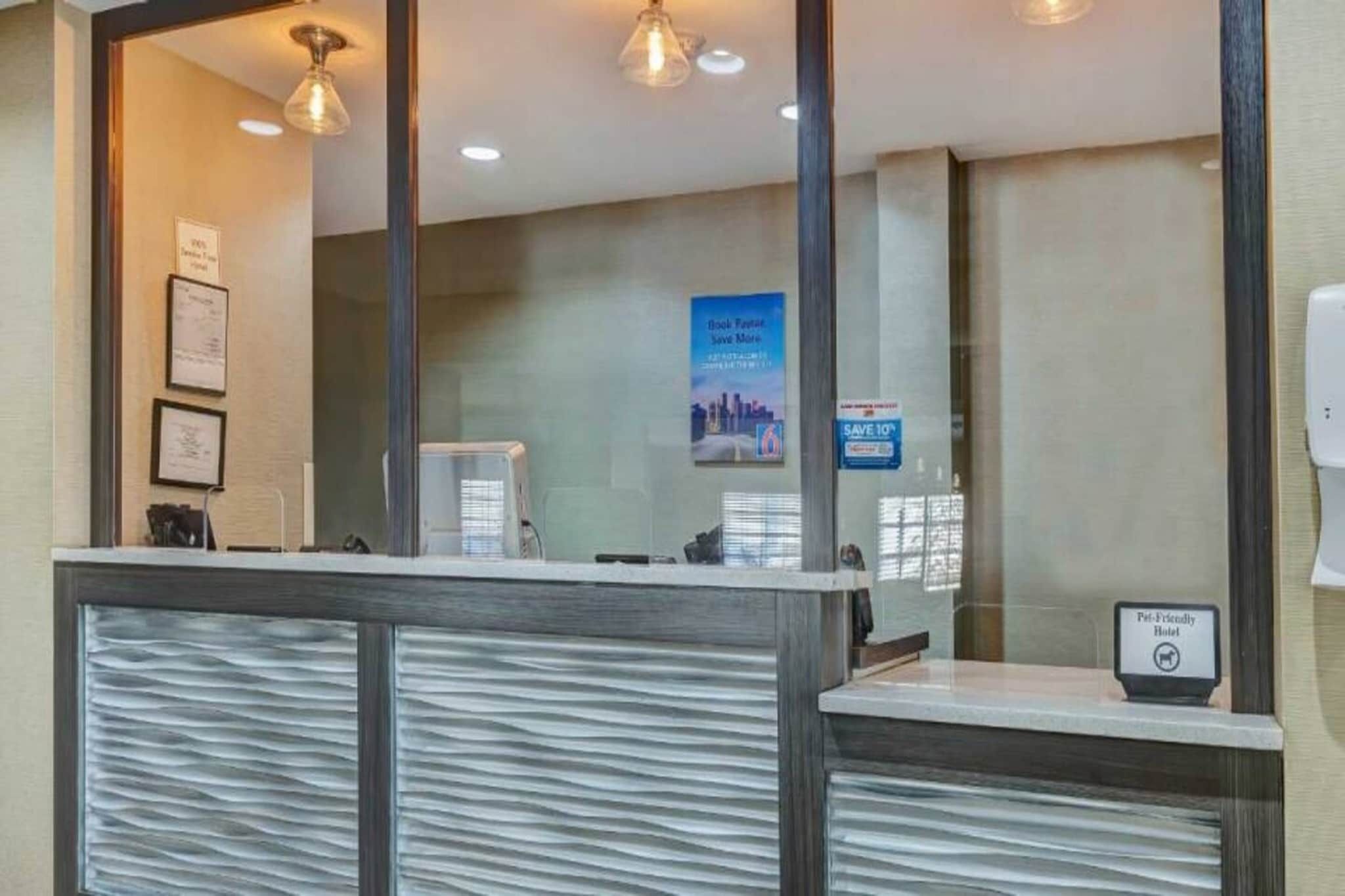 A reception desk with a modern design, a framed sign above it, and a poster on the wall.