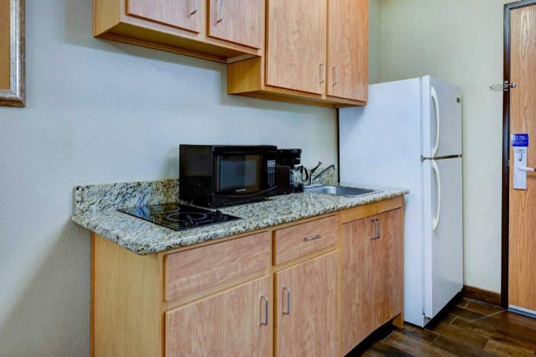 A compact kitchen with a microwave, coffee maker, and a refrigerator.