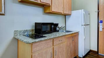 A compact kitchen with a microwave, coffee maker, and a refrigerator.