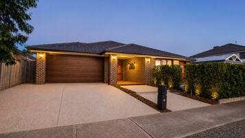 A residential house with a garage, brick exterior, and a well-lit driveway.