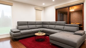 Una sala moderna con un sofá seccional gris, una mesita redonda y una alfombra roja.