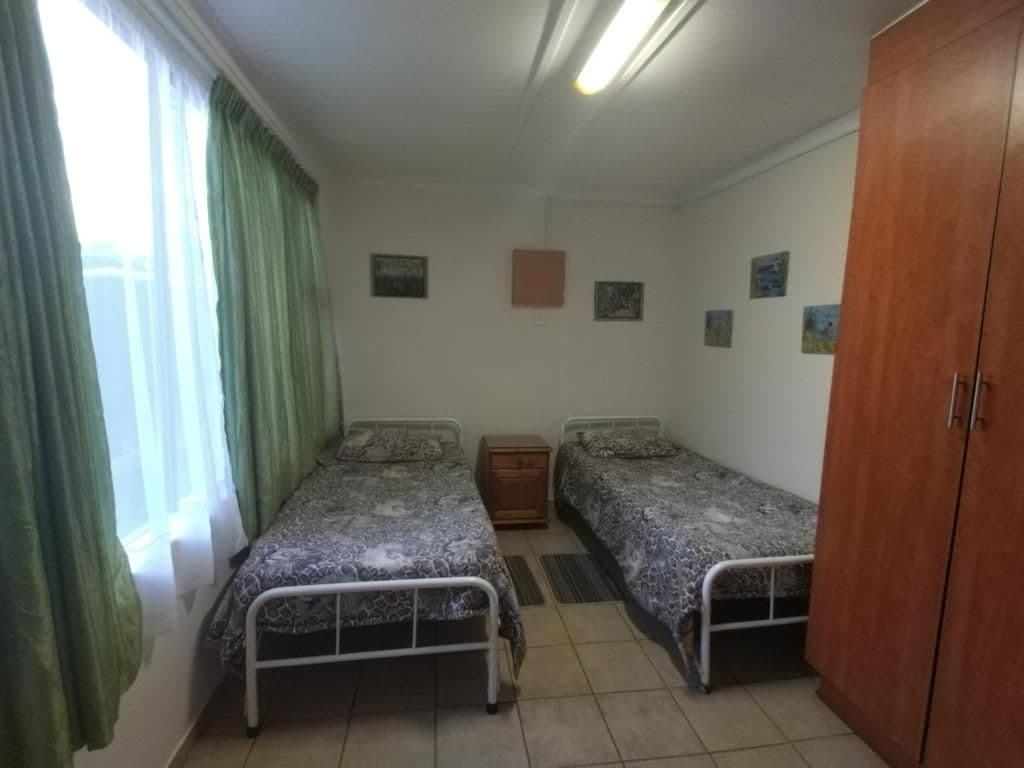 A room with two single beds, a wooden wardrobe, and a small bedside table.